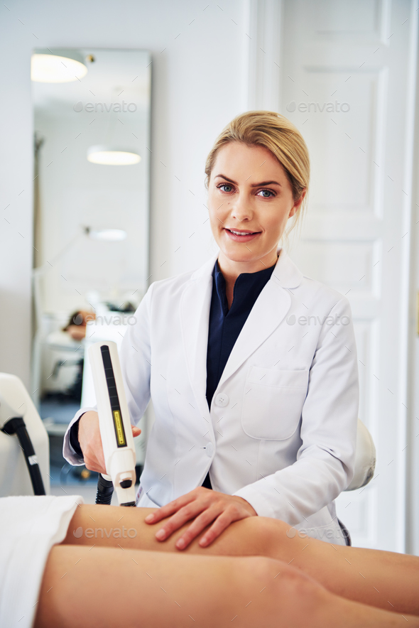 Smiling clinic technician performing electrolysis on a client s